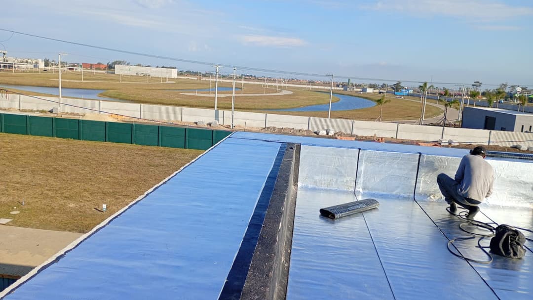 Detalhe da aplicação de primer em uma laje de concreto, preparando a superfície para a impermeabilização.