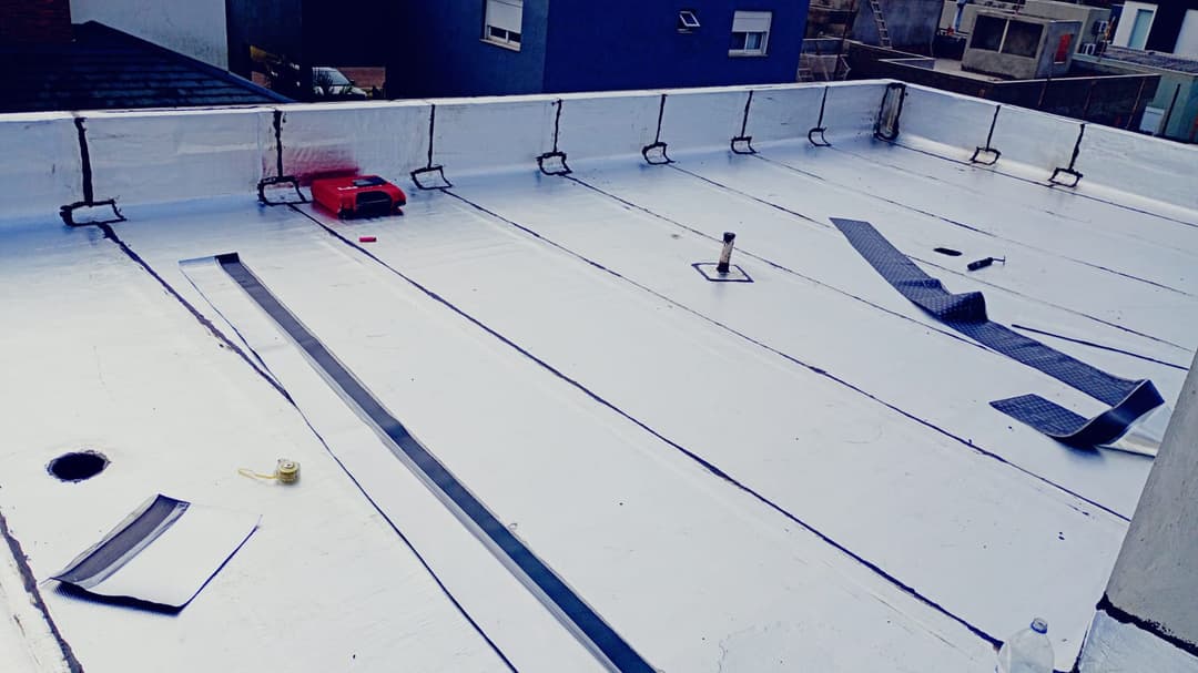 Equipe da Strauss aplicando manta asfáltica em uma ampla laje comercial.