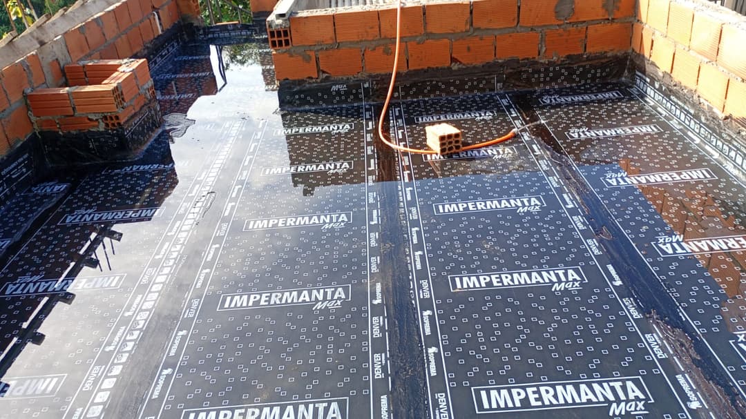 Impermeabilização de laje residencial com manta asfáltica sendo aplicada.